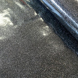 A black high gloss plastic fabric with glitter sprinkled all over. Kayes Textiles Fabrics.