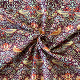 A damson background cotton with a symmetrical bird and floral design. Kayes Textiles Fabrics.