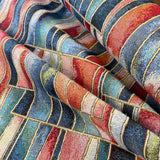 A heavy tapestry fabric with a geometric design in blues and reds with gold outlining. Kayes Textiles Fabrics.