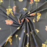 A polyester jersey in navy with different directional flowers in pink, white, yellow and green. Kayes Textiles Fabrics