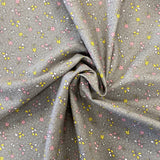 A grey cotton with a small floral print in pink and yellow all over the fabric with a speckled white spot. Kayes Textiles Fabrics.