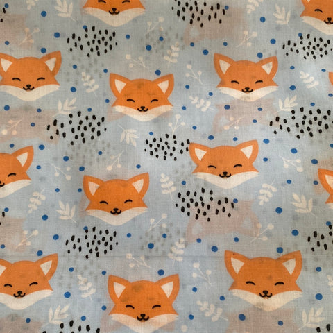 A pale blue polycotton fabroic with a fox face and dotty patches repeated over the fabric. 