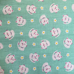 A mint coloured fabric with small white cartoon cats all over. Kayes Textiles Fabrics