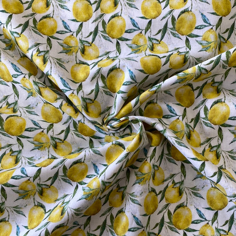 A white cotton fabric with lemons with leaves all over the fabric. Kayes Textiles Fabrics