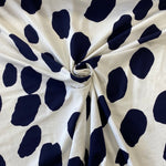 A viscose jersey fabric in white with large navy irregular spots on it. Kayes Textiles Fabric
