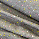 A grey cotton with a small floral print in pink and yellow all over the fabric with a speckled white spot. Kayes Textiles Fabrics.