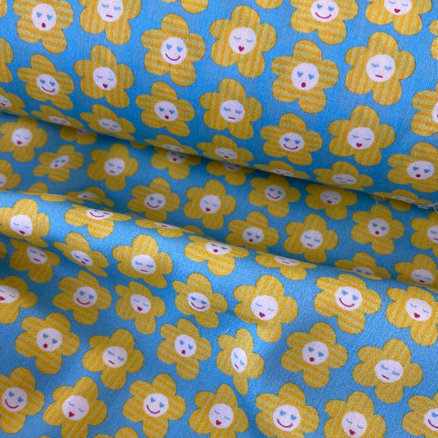 An aqua background fabric with yellow flower faces all over. Kayes Textiles Fabrics