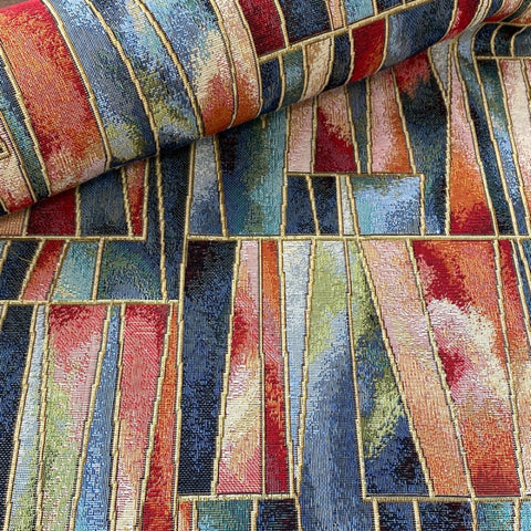 A heavy tapestry fabric with a geometric design in blues and reds with gold outlining. Kayes Textiles Fabrics.