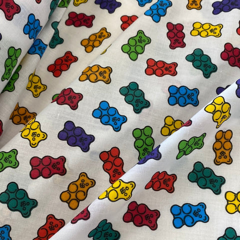 A white fabric with different coloured gummy bears all over. Kayes  Textiles Fabrics. 