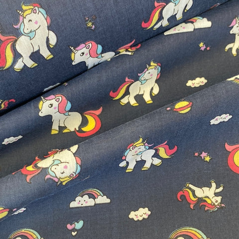A navy fabric with a small unicorn character and rainbows all over. Kayes Textiles Fabrics
