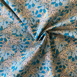A beige background fabric with an all over blue leaf and floral pattern all over. Kayes Textiles Fabrics