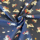 A navy fabric with a small unicorn character and rainbows all over. Kayes Textiles Fabrics