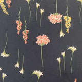 A polyester jersey in navy with different directional flowers in pink, white, yellow and green. Kayes Textiles Fabrics