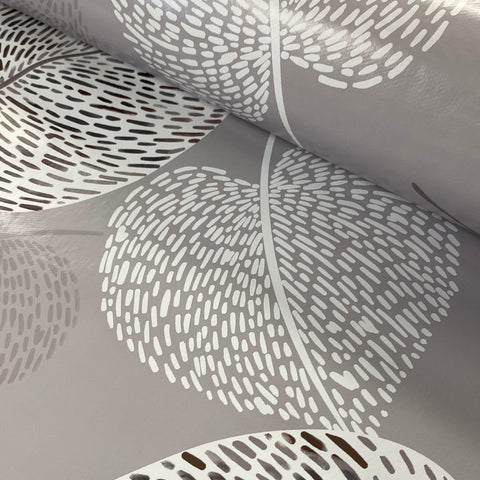 A grey plastic fabric with a large leaf design in white speckled effect. Kayes Textiles Fabrics. 