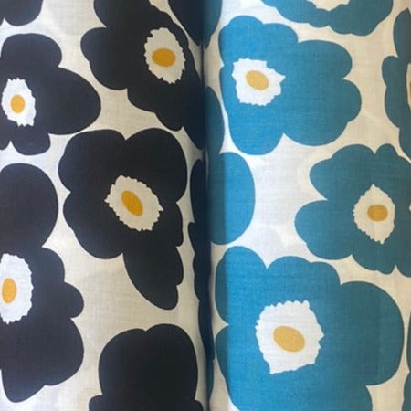 Two rolls of white viscose fabric, one with large black pansy flowers and the other one with large blue pansy flowers. Kayes Textiles Fabrics