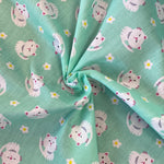 A mint coloured fabric with small white cartoon cats all over. Kayes Textiles Fabrics