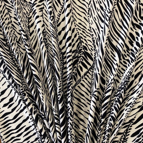 A polyester jersey in a cream colour with black animal print style line design. Kayes Textiles fabrics