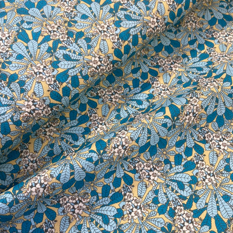 A beige background fabric with an all over blue leaf and floral pattern all over. Kayes Textiles Fabrics