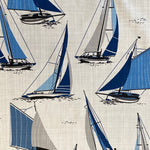A white cotton fabric with sailing boats all over in shades of blue and grey. Kayes Textiles Fabrics.