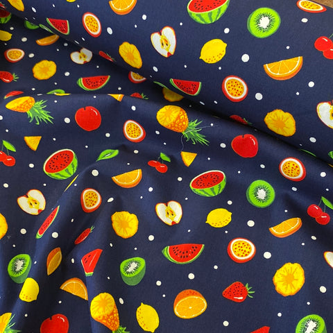 A navy cotton fabric with small fruit salad items all across the fabric icluding watermelons, lemons and apples. Kayes Textiles Fabrics. 