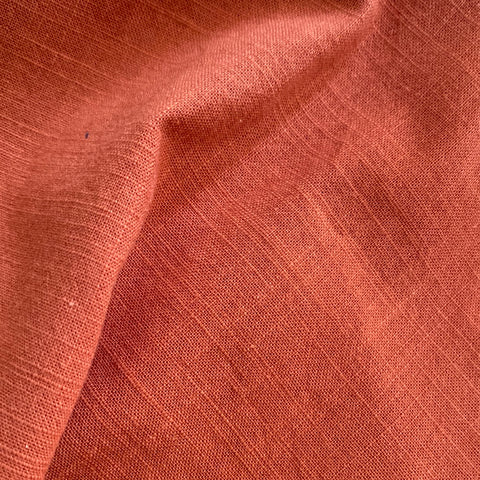 A plain cotton fabrtic with a textured weave in a burnt orange colour