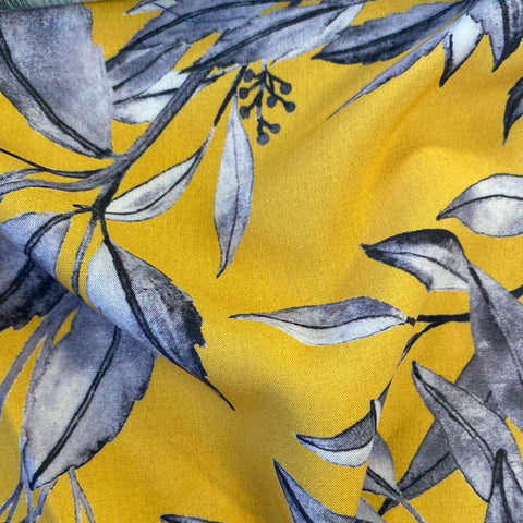 A floaty viscose fabric with grey leaves on a yellow background Kayes Textiles Fabrics