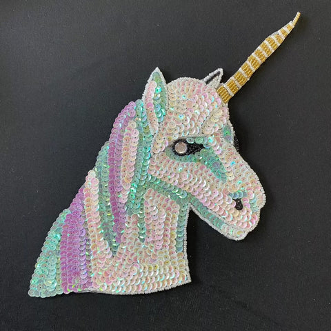 A motif made up of white, lilac and turquoise sequins creating a unicorns head shape. Kayes Textiles Fabrics