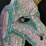 A motif made up of white, lilac and turquoise sequins creating a unicorns head shape. Kayes Textiles Fabrics